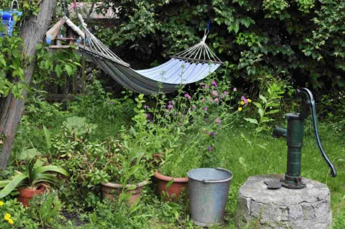 Hängematte neben Wasserpumpe,, darunter Kübel