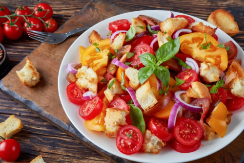 Tomatensalat mit gerösteten Brotwürfeln und Basilikum auf einem Holztisch Foto: AdobeStock_myviewpoint