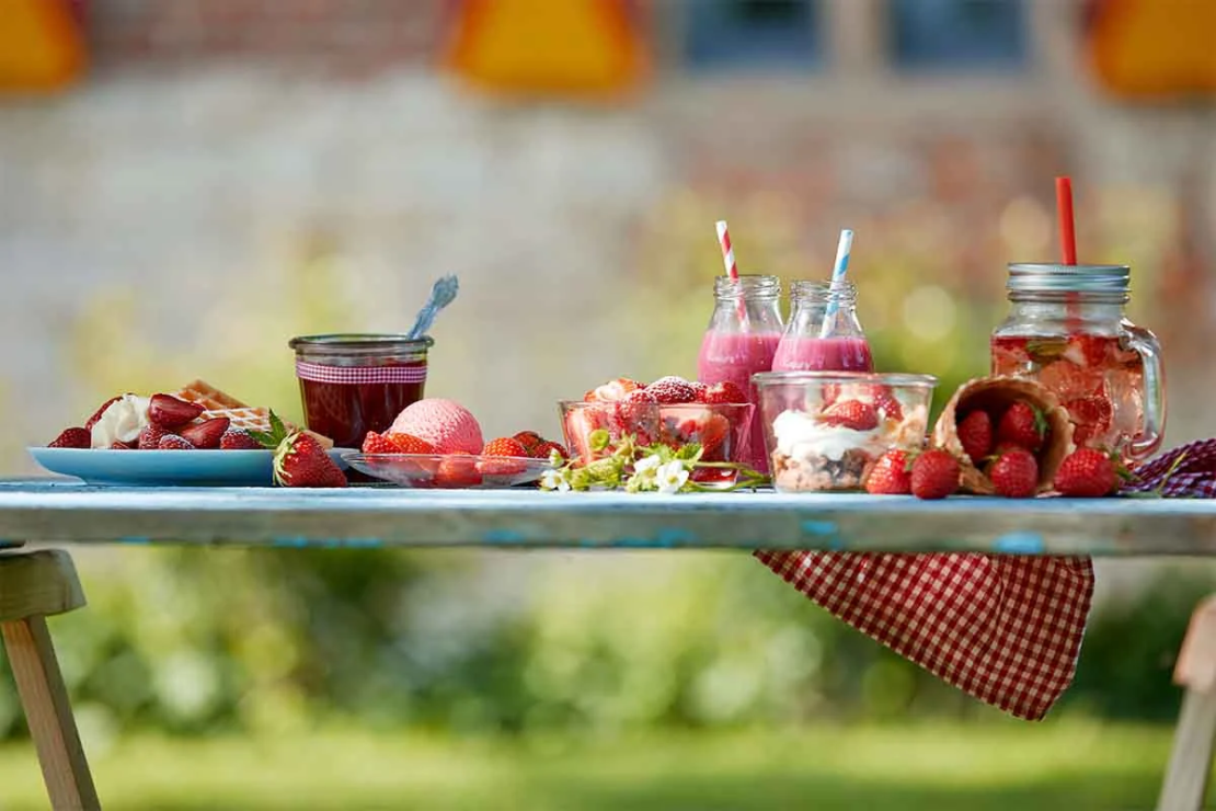 Erdbeereis neben anderen Erdbeerspezialitaeten auf einem Gartentisch [Foto: AdobeStock_Exclusive-Design]