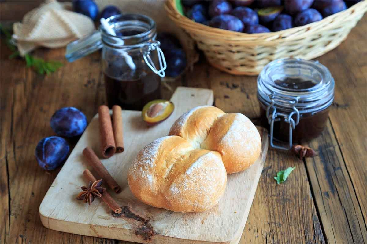 Pflaumenmus auf einem Tisch neben Sonntagsbroetchen und Gewuerzen [Foto: AdobeStock_Juefrateam]