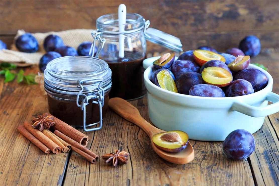 Pflaumenmus im Glas neben Pflaumen in einer Schale [Foto: AdobeStock_Juefrateam]