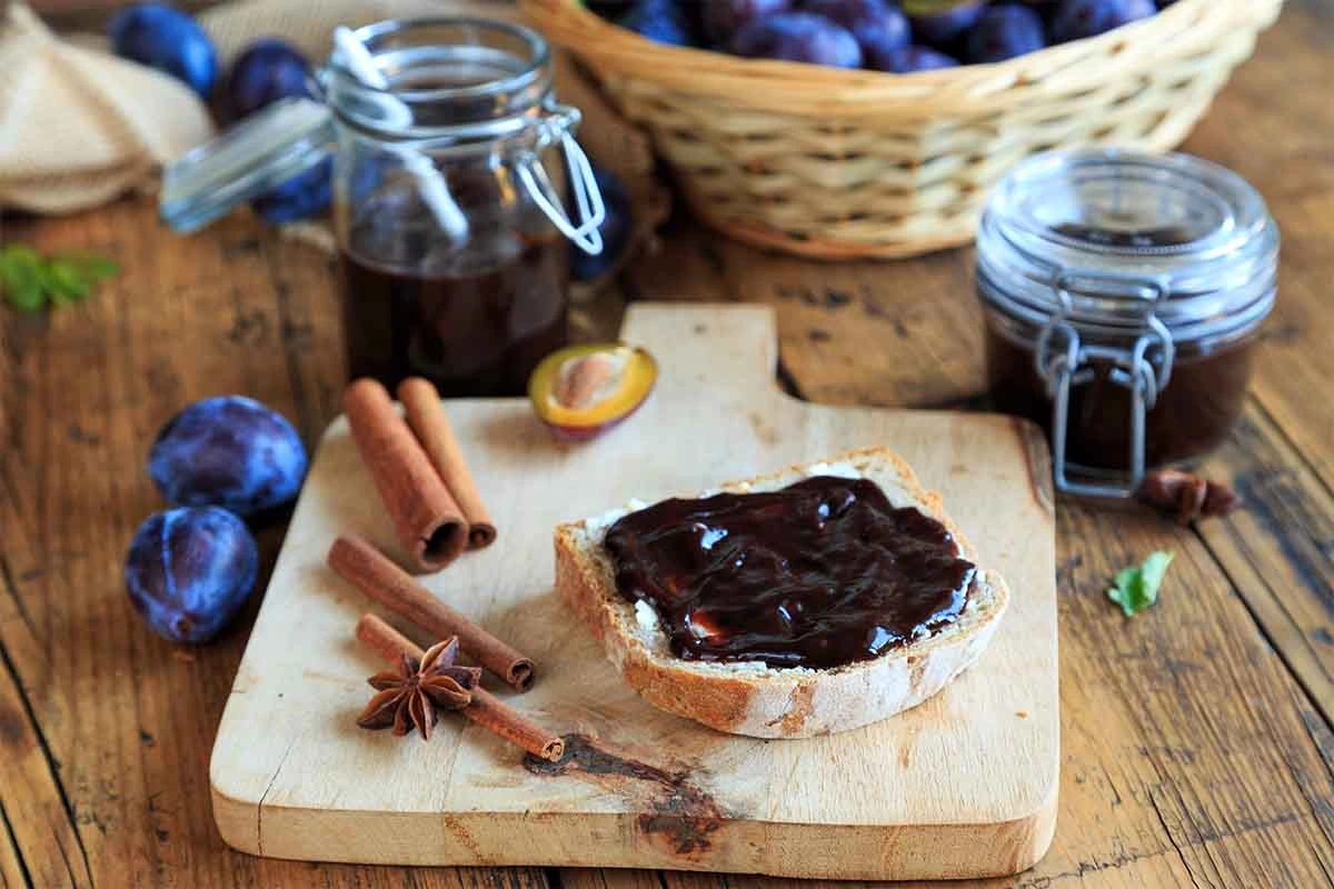 Pflaumenmus neben Gewuerzen und auf einem Weißbrot [Foto: AdobeStock_Juefrateam]