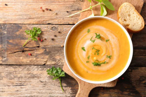 Moehrensuppe in einer weißen Schale auf einem Holzbrettchen [Foto: AdobeStock_M.studio]