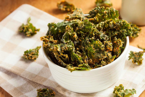 Kale-Chips in einer Schale auf einem beige-weiß karierten Kuechentuch [Foto: AdobeStock_Brent Hofacker]