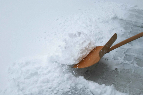 Hoelzerne Schneeschaufel schiebt Schnee, um Platz fuer Streusalz-Alternativen zu machen. [Foto: AdobeStock_momanuma]